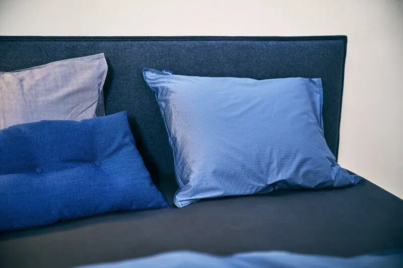 Blauw gestoffeerd Auping-hoofdbord met kussens in drie tinten blauw