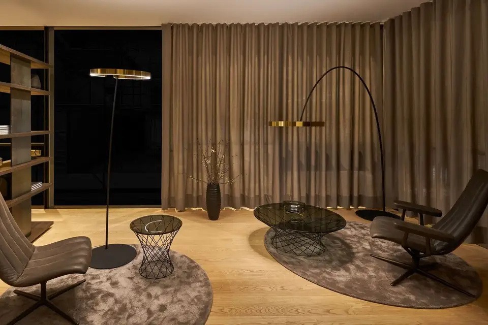Twee vloerlampen met messing ringen in een rustige zitkamer bij avond