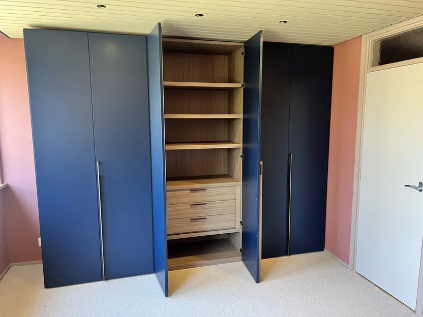 Dezelfde kast met twee deuren open: lichte houten legplanken en drie laden