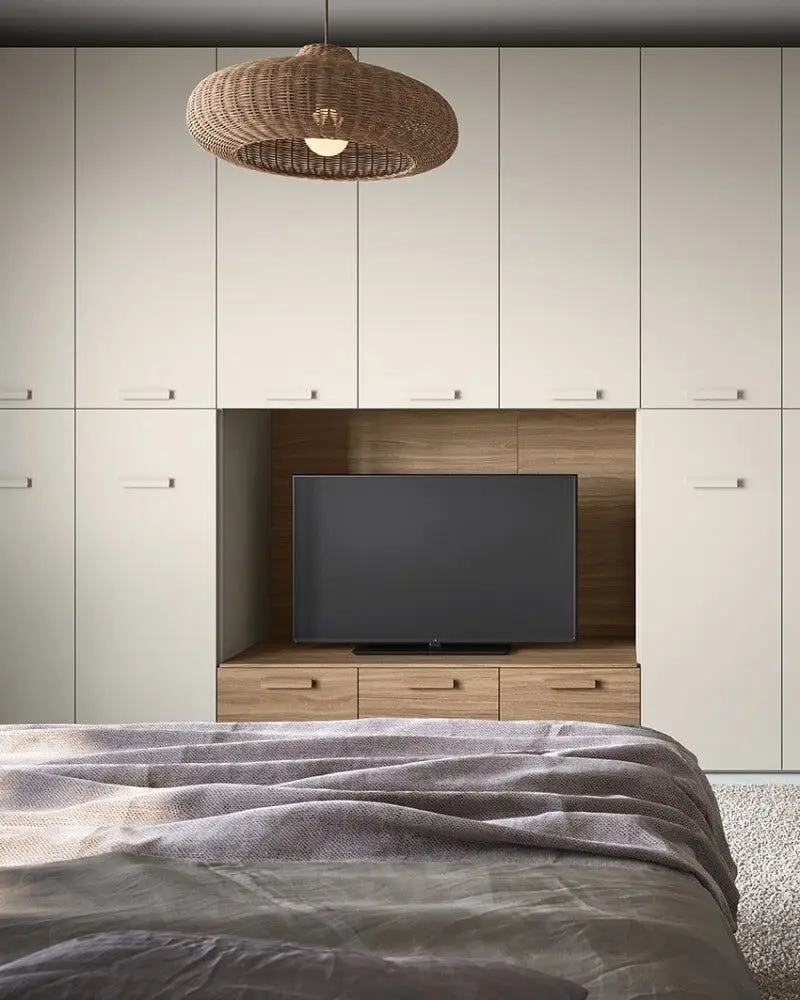 Lichte kastenwand achter een bed, met een houten nis voor de televisie en een werkblad aan de zijkant