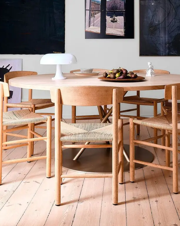 Een witte tafellamp op een ronde houten eettafel met rieten stoelen