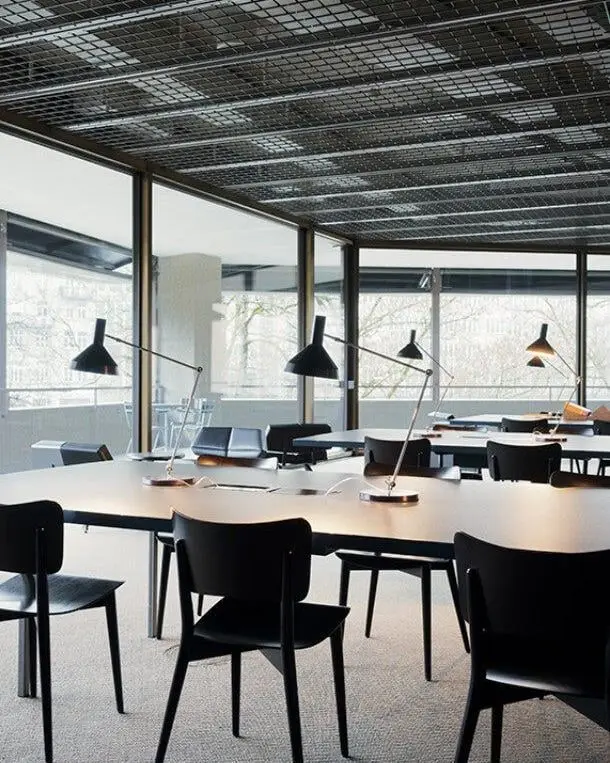 Zwarte lampen boven lange tafels in een restaurant met grote ramen