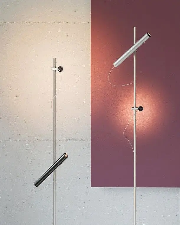 Een slanke vloerlamp met twee lichtstaven voor een paarse wand