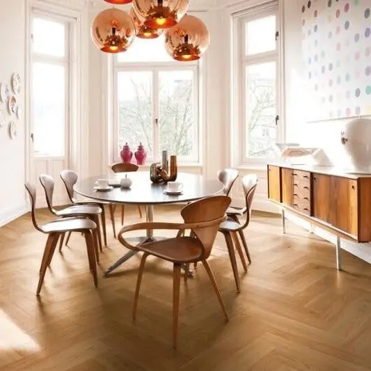 Eetkamer met een ronde tafel en koperen hanglampen op een eiken visgraatvloer
