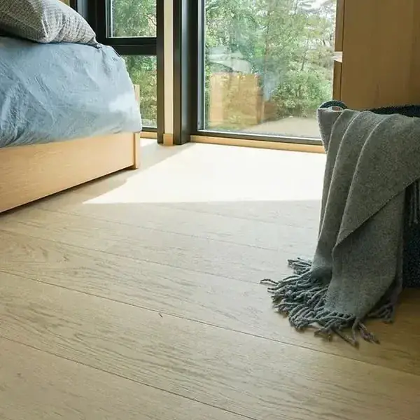 Zolderslaapkamer met een groot raam en een lichte eiken plankenvloer
