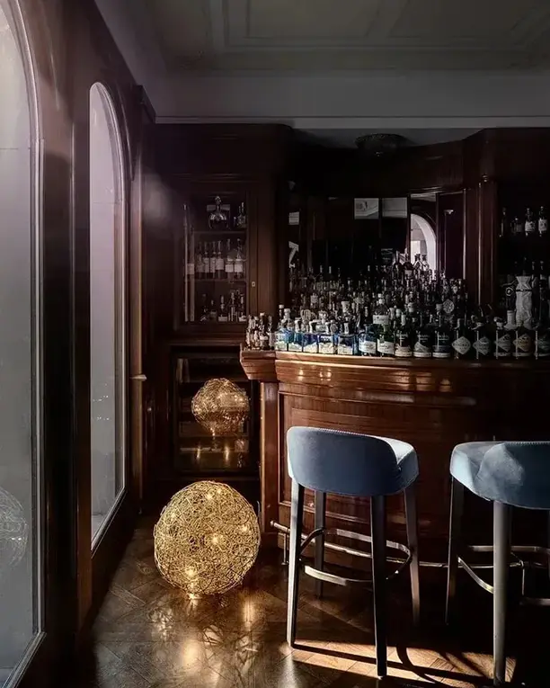 Een donkere bar met barkrukken en een gloeiende bol van gouden draad op de vloer