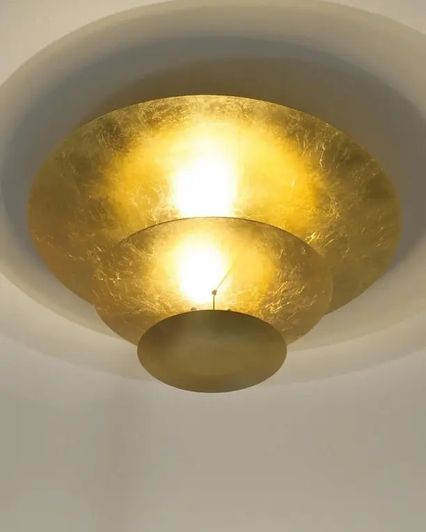Een gouden plafondlamp in lagen, van dichtbij en van onderen gezien