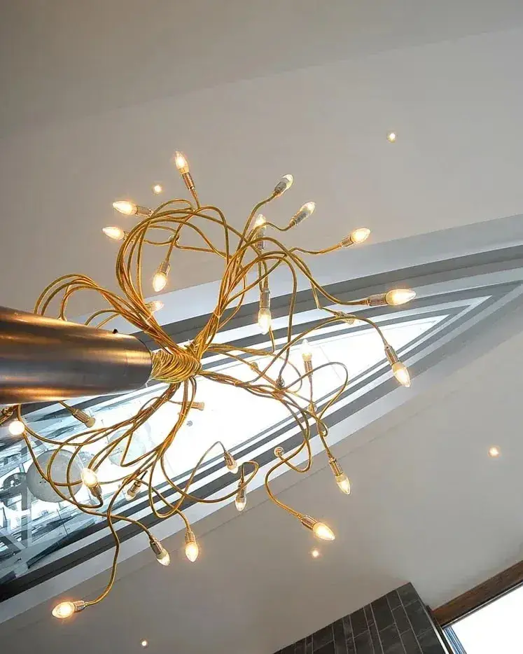 Gouden takken met kleine lichtpunten, van onderen gezien onder een schuin glazen dak