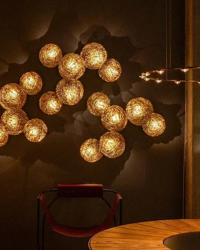 Een groep gloeiende gouden bollen op een donkere wand boven een ronde tafel