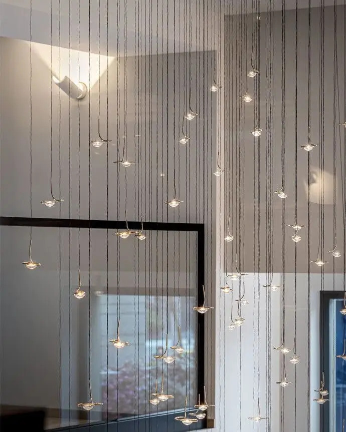 Tientallen kleine lichtpunten aan dunne kabels op verschillende hoogtes in een hoge kamer