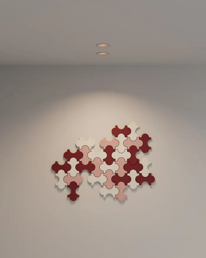 Een kleine spot in het plafond die een rood en roze wandkunstwerk op een lichte wand aanlicht