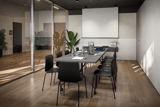Vergaderzaal met een lange tafel, zwarte stoelen en een glazen wand