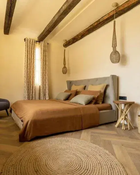 Slaapkamer met houten balken, roestbruin linnen en een rond jute kleed op visgraat