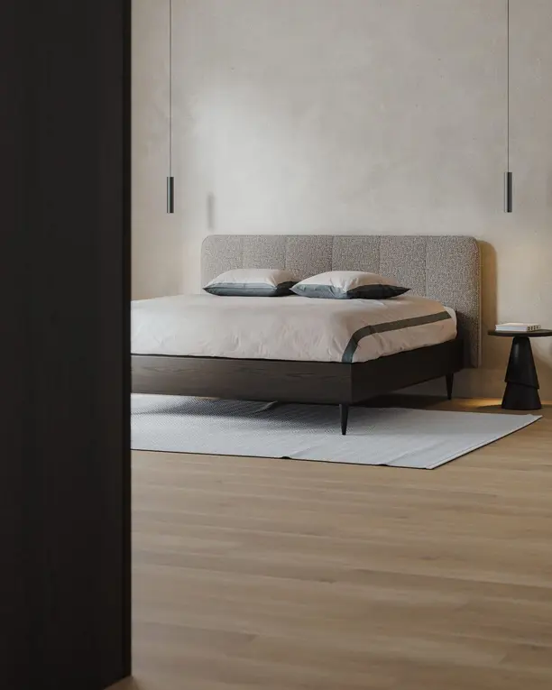 Doorkijk langs een donkere houten wand naar een bed met een donker eiken frame en een kalkwand