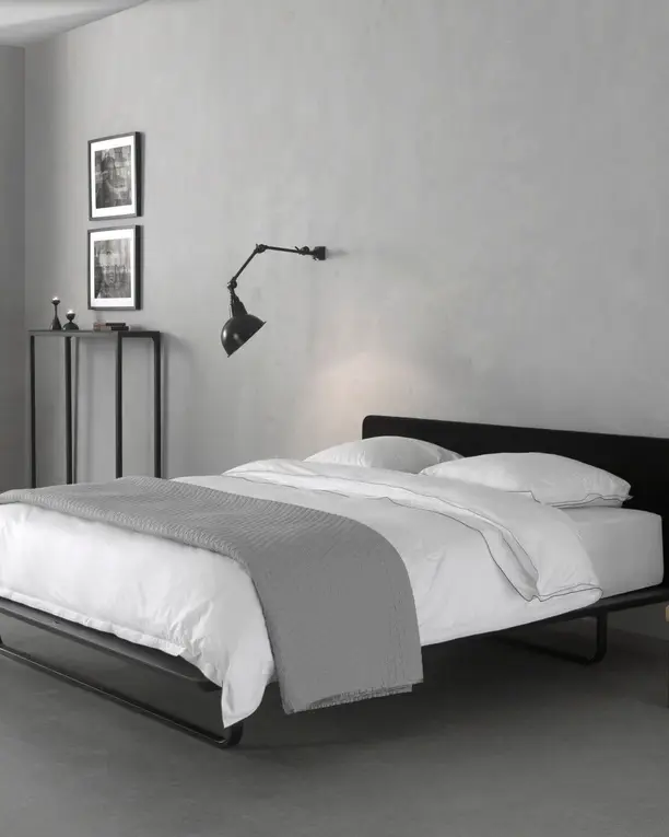 Het Less bed in zwart met wit en grijs beddengoed in een lichte stadskamer