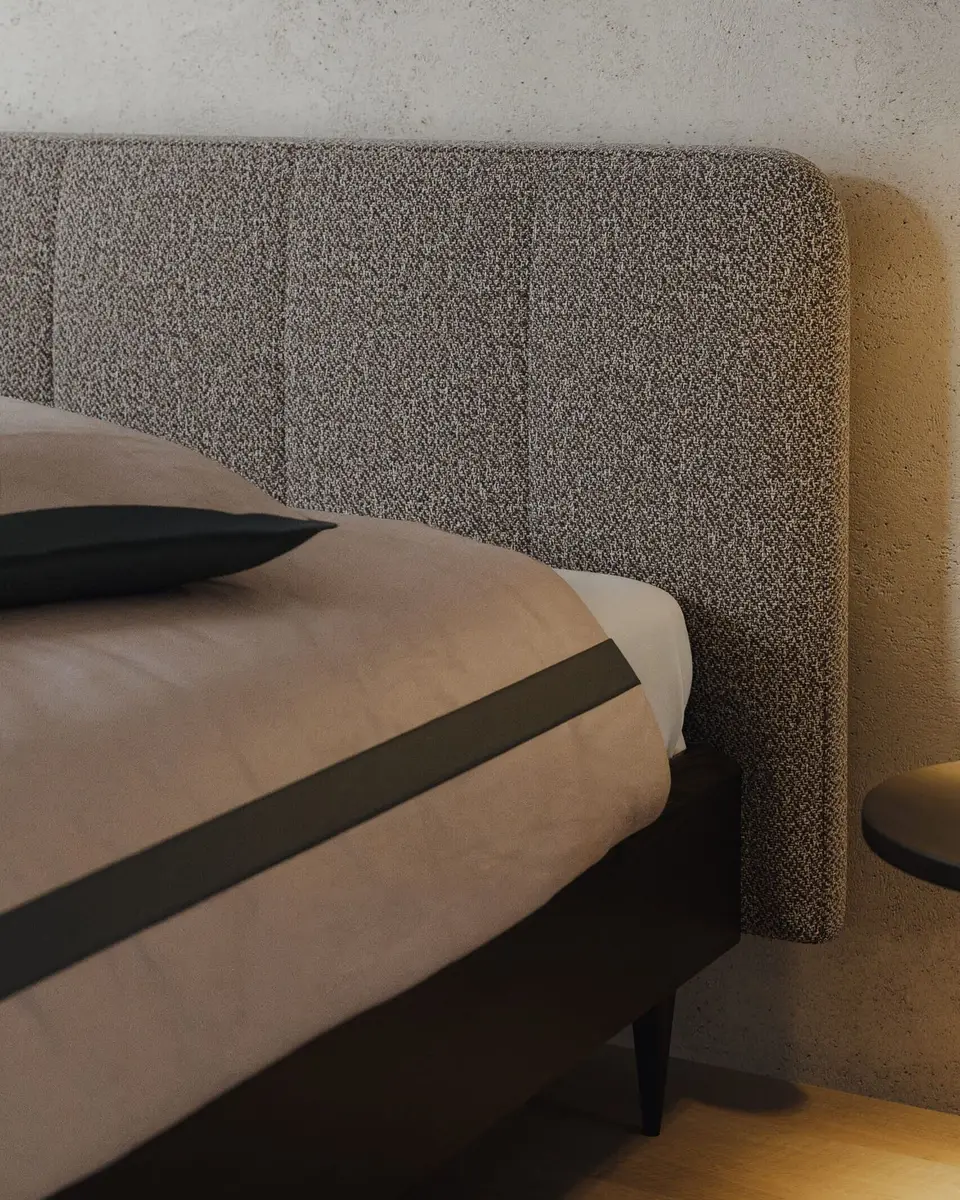 Een gestoffeerd hoofdbord in boucle naast een bed met een donker eiken frame, in warm avondlicht