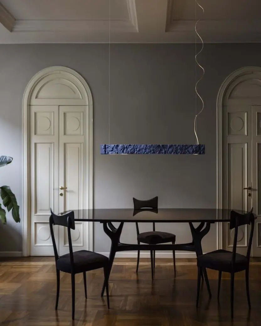 Een eetkamer met twee hoge boogdeuren, een ronde tafel en stoelen op een houten vloer