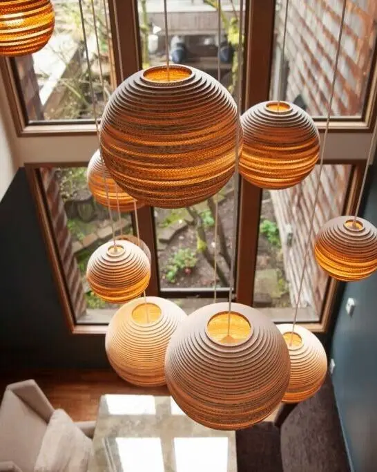Een cluster bolvormige lampen van karton in een hoog trappenhuis, van bovenaf gezien