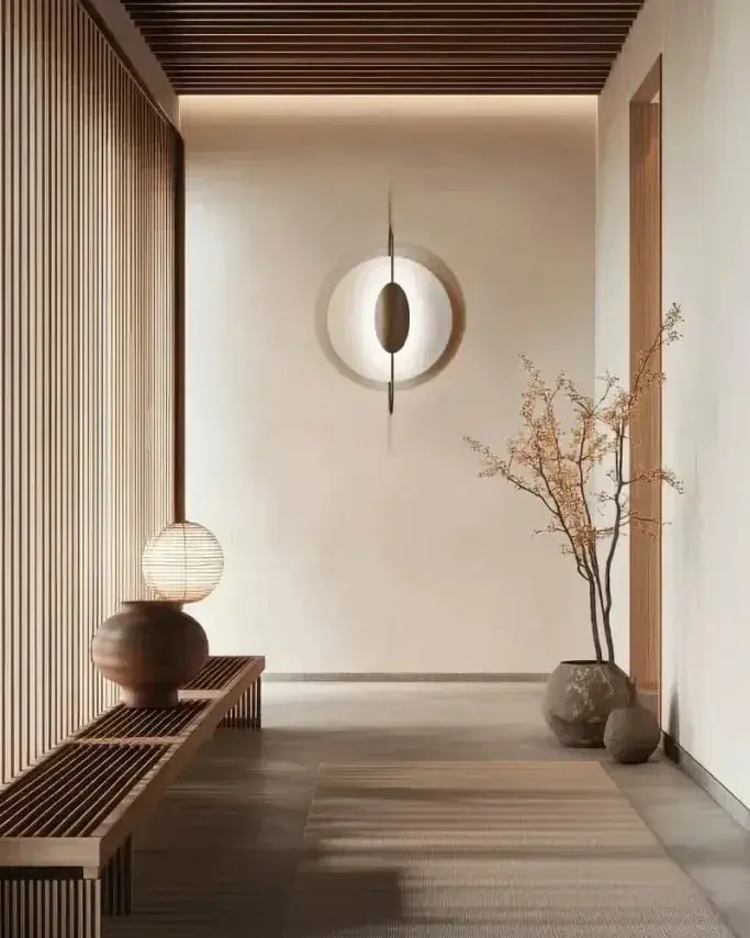 Een ronde wandlamp in een gang met een houten plafond, een bank en vazen