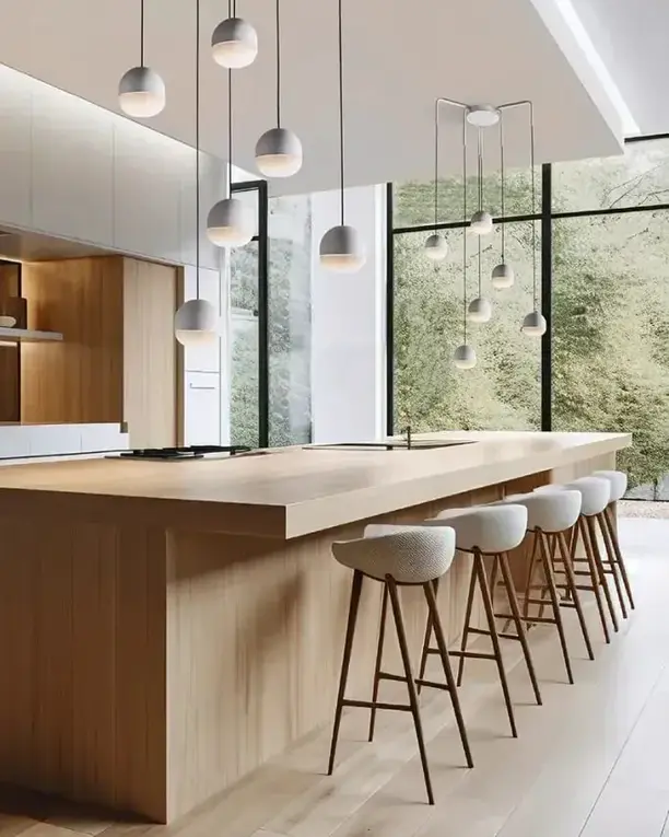 Een groep kleine koepelhanglampen boven een lang houten keukeneiland met barkrukken