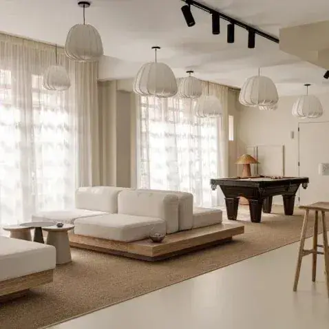 Lichte loungeruimte met een lage bank en een biljarttafel op sisal