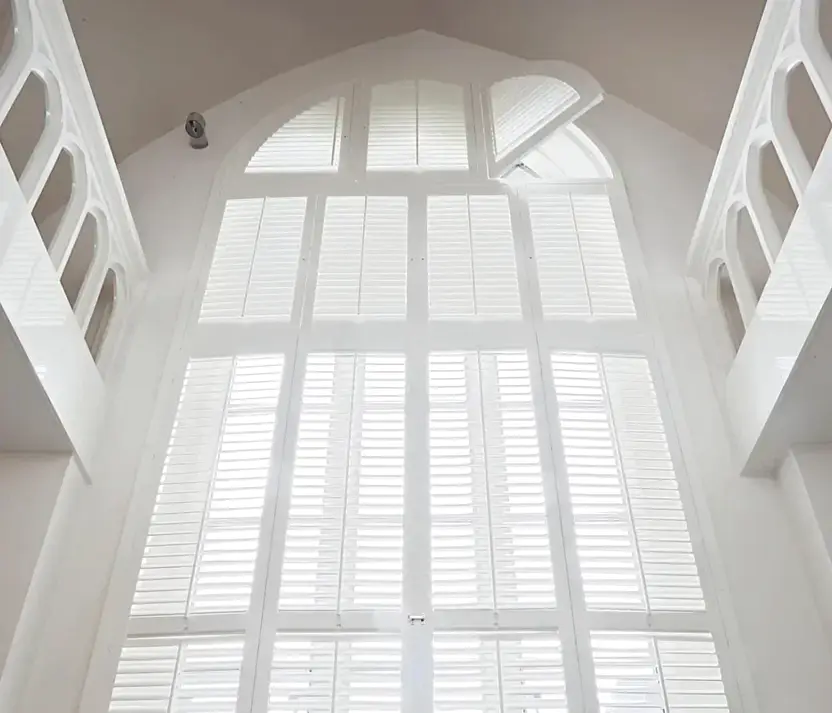 Hoog boograam in een oud gebouw, van onder tot boven gevuld met witte shutters