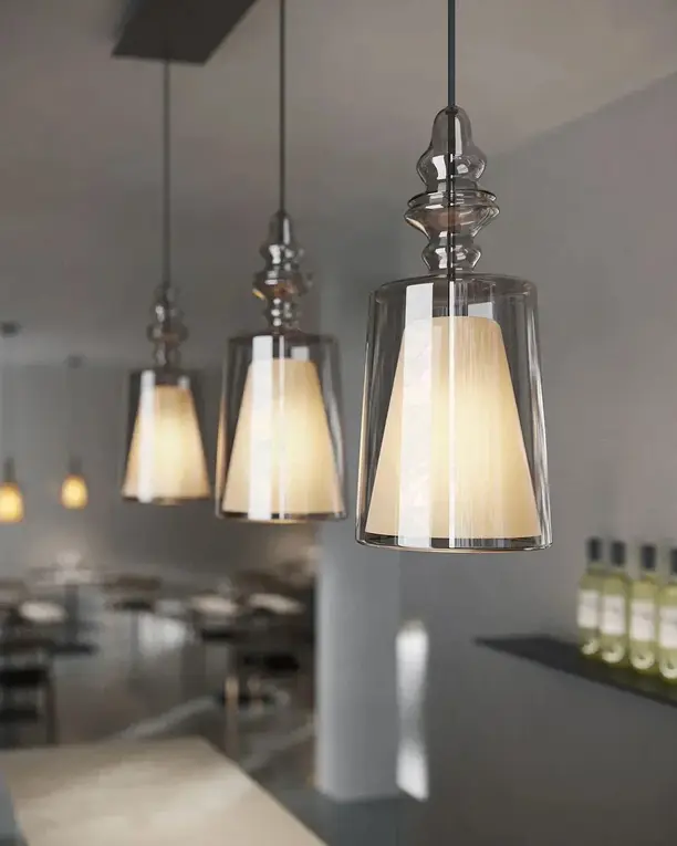 Glazen hanglampen met stoffen kappen boven een bar met flessen