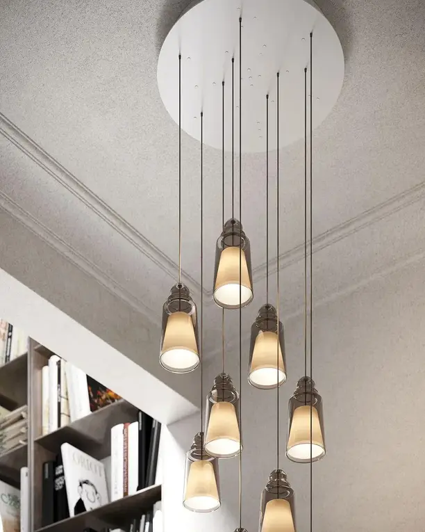 Een groep glazen hanglampen op verschillende hoogtes in een licht trappenhuis