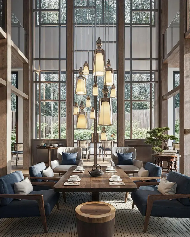 Een cascade van glazen hanglampen met kappen in een hoge lounge met stalen ramen