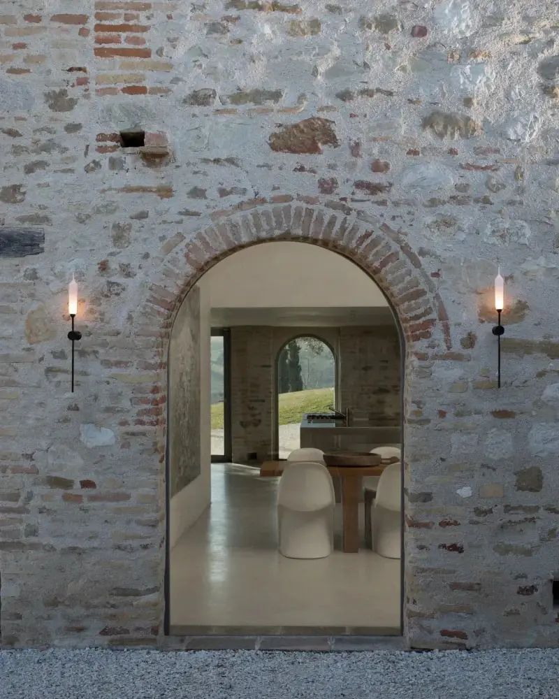 Twee lichtstelen aan een bakstenen muur naast een boogvormige doorgang