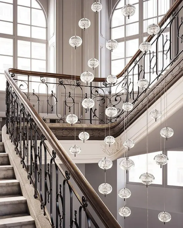 Een lange cluster van glazen bollen in een trappenhuis met een smeedijzeren leuning