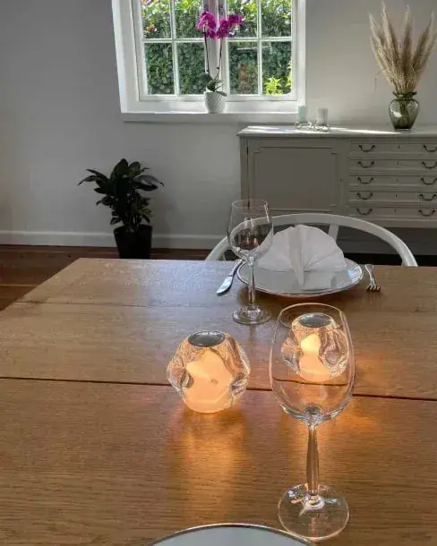 Een helder lampje tussen wijnglazen op een gedekte houten eettafel
