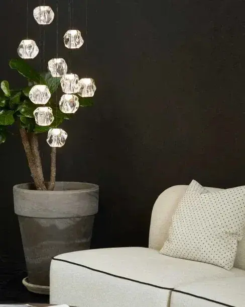 Een tros heldere bollen voor een donkere wand naast een plant en een witte bank