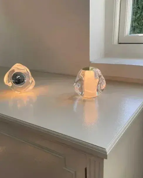 Twee kleine heldere lampjes op een witte kast bij het raam