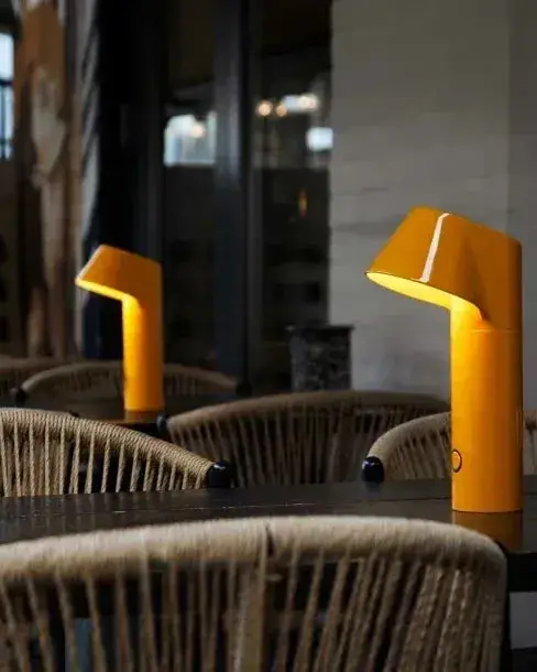 Gele tafellampen op tafels met rieten stoelen op een terras