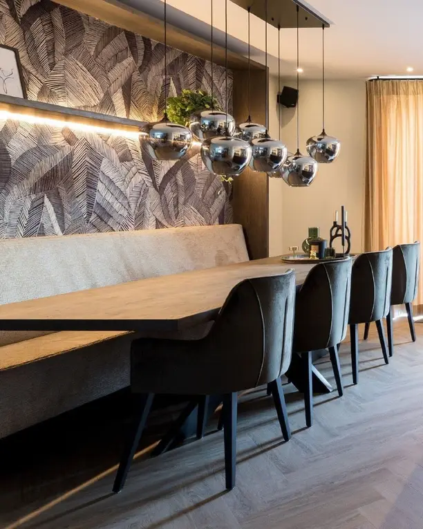 Lange eettafel met een bank en glazen hanglampen op een warme visgraatvloer