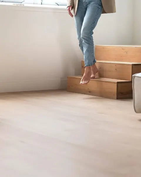 Blote voeten op een eiken trap boven een lichte plankenvloer in pvc