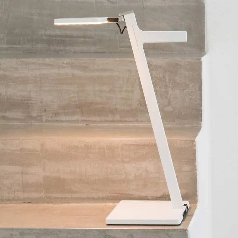 Een witte bureaulamp met een platte kop op een betonnen trede