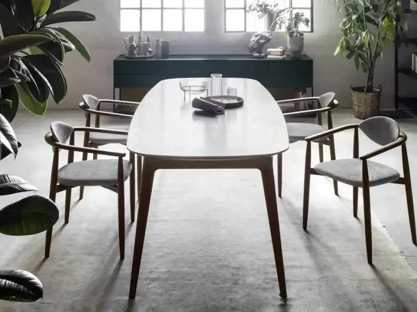 Ovale eettafel met houten stoelen in een loft, een dressoir op de achtergrond