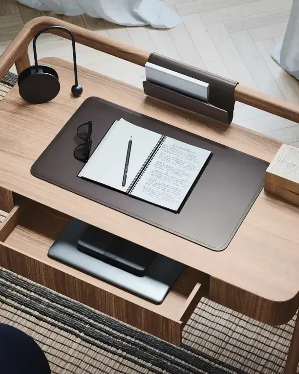 Houten bureau met een leren onderlegger, een lamp en een notitieboek, van boven gezien