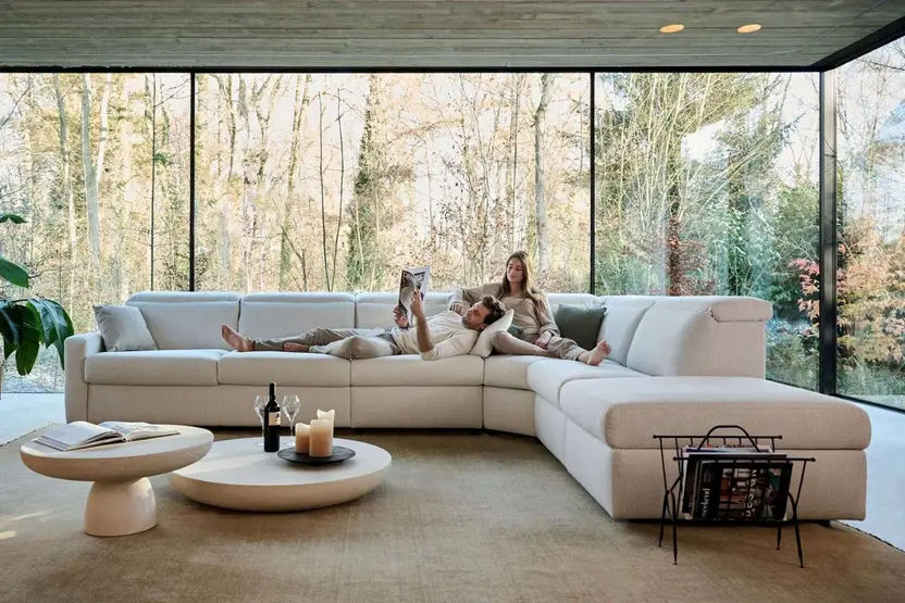 De hoekbank Agio in een ruime glazen woonkamer, met twee mensen die lezen en twee ronde salontafels