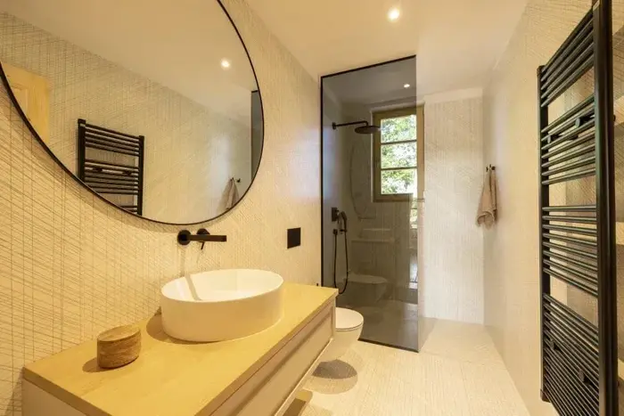 Badkamer met een ronde spiegel, een eiken meubel en een inloopdouche
