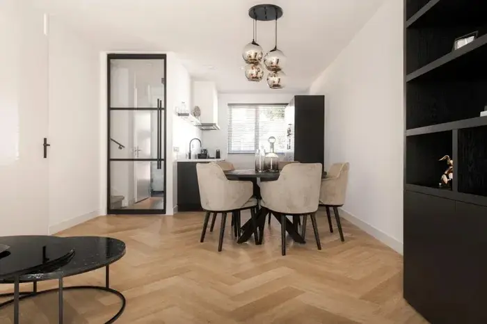 Eethoek met een ronde tafel, een glazen deur en koperen hanglampen op visgraat