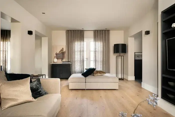 Woonkamer met brede, natuurlijke eiken planken, linnen gordijnen en een crème bank