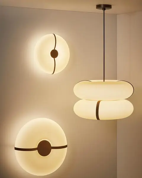 Twee ronde wandlampen en een hanglamp van amberkleurig glas met een donkere band, gloeiend op een warme wand
