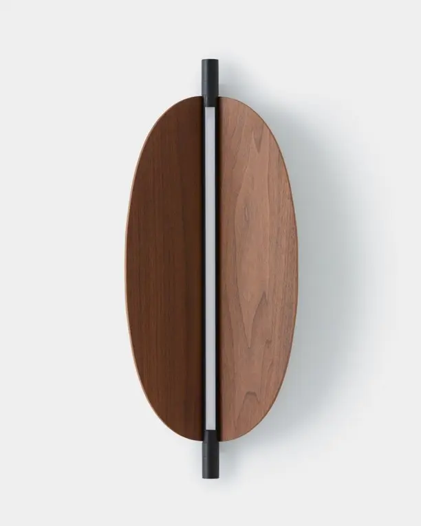 Een ovale wandlamp van notenhout met een verticale lichtlijn, op een lichte achtergrond