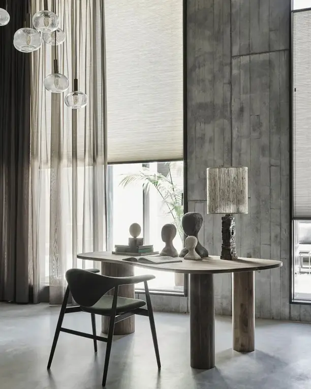 Hoge ramen met plissé en lichte inbetweens in een loft met betonnen wanden en glazen hanglampen