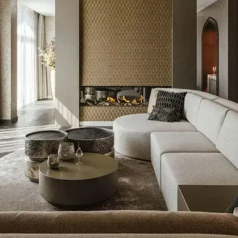Zithoek met een lange witte bank en bronzen bijzettafels op een donker karpet