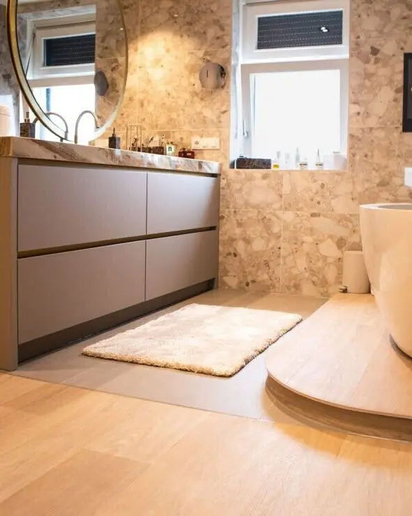 Badkamer met een vrijstaand bad op een verhoging en een warme eiken vloer