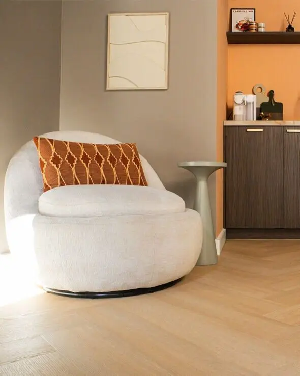 Ronde witte fauteuil voor een barkast op een lichte visgraatvloer